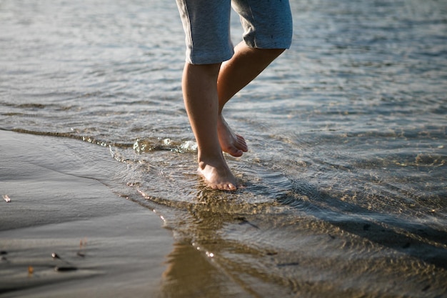 Menino brincando na praia nas férias de verão Crianças na natureza com bela areia do mar e azul correndo na água do mar