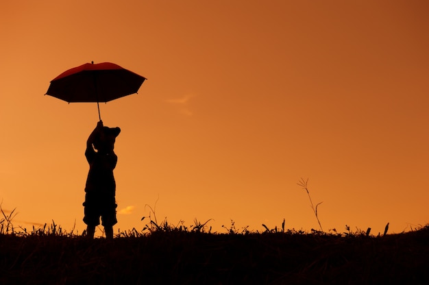 menino brincando no campo de grama ao pôr do sol