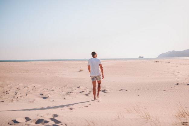 Menino caminhando na praia ao pôr do sol