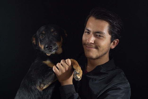 Menino carregando e abraçando seu cachorro, ambos posando para a foto, o cachorro tem um rosto terno e feliz, sente o amor de seu humano e se diverte.