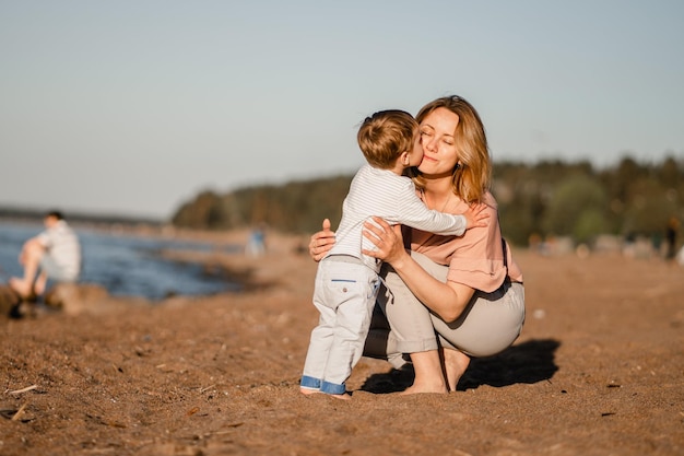 Menino caucasiano bonito e mãe feliz juntos na costa