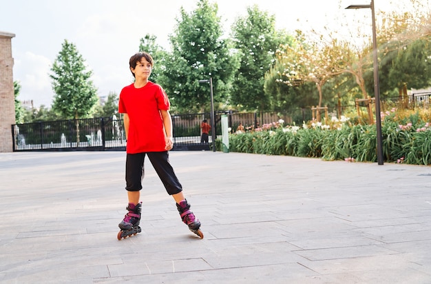 Menino caucasiano brincando com patins no parque.