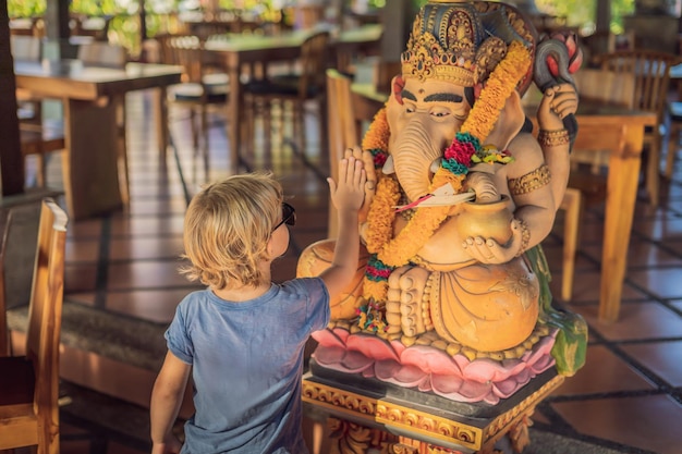 Menino caucasiano high-five Ganesha. Conhecendo o conceito de cultura ocidental e oriental. orientais e ocidentais. Viajar para a Ásia com crianças