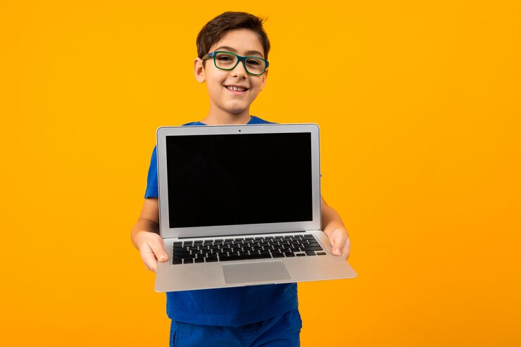 Menino caucasiano mantém a tela do laptop em amarelo