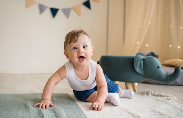 Foto menino caucasiano rasteja no chão no quarto das crianças com brinquedos infância feliz