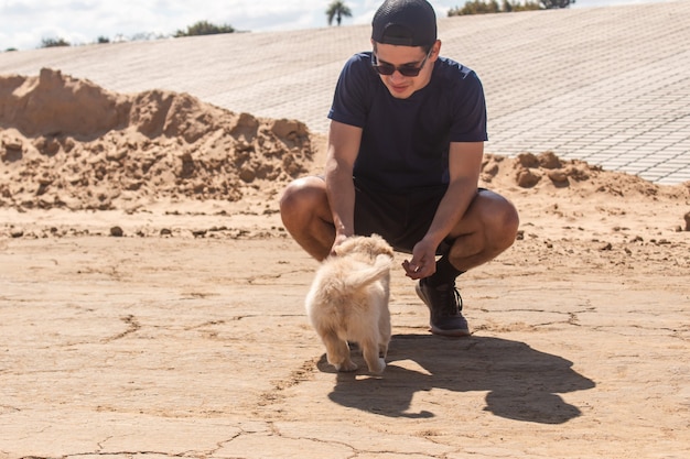 Menino chamando seu cachorro para se juntar a ele na areia.