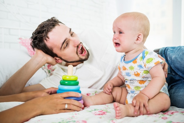 Menino chorando se senta perto de um pai reconfortante e brinquedos. o conceito de crianças travessas.