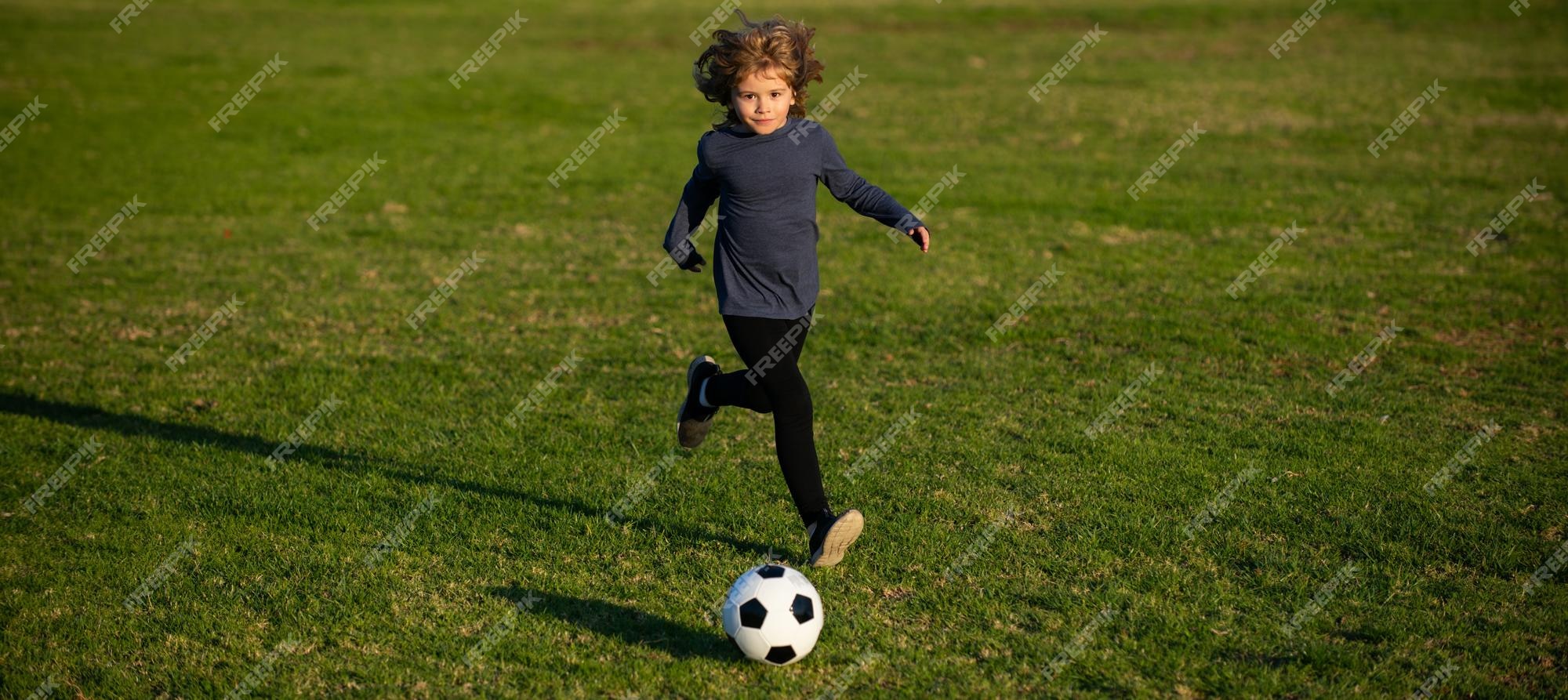 Dois Jogadores De Futebol Chutando Bola De Futebol Em Um Jogo. Meninos Da  Escola Jogam Competição Esportiva. Duas Crianças Multirraciais Jogando  Partida De Futebol. Crianças Em Uniformes De Futebol Verde E Azul