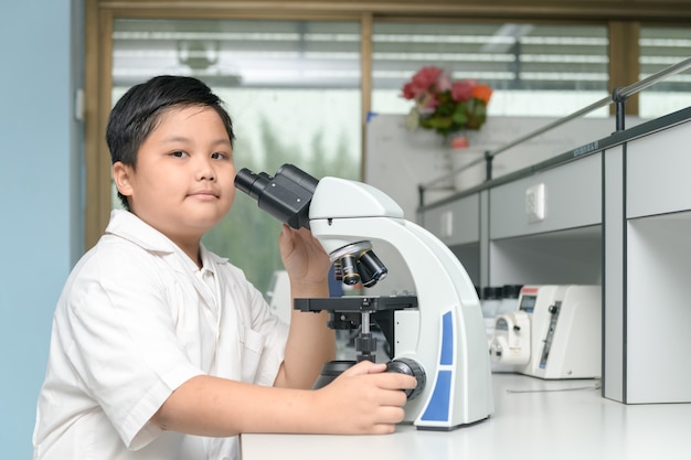 menino cientista trabalhando com microscópio no conceito de laboratório, ciência e educaton