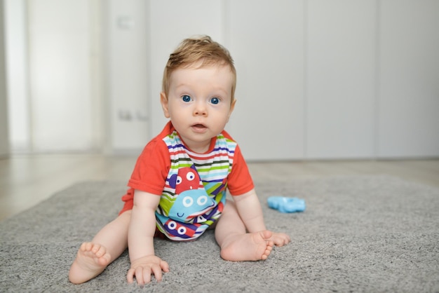 Menino com brinquedos sentados no tapete em casa Criança adorável se divertindo