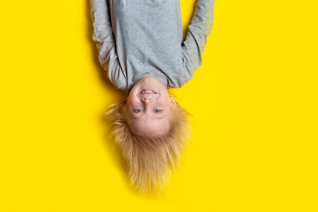 Menino com cabelo loiro isolado em amarelo