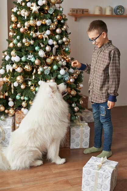 Menino com cachorro perto de árvore de natal