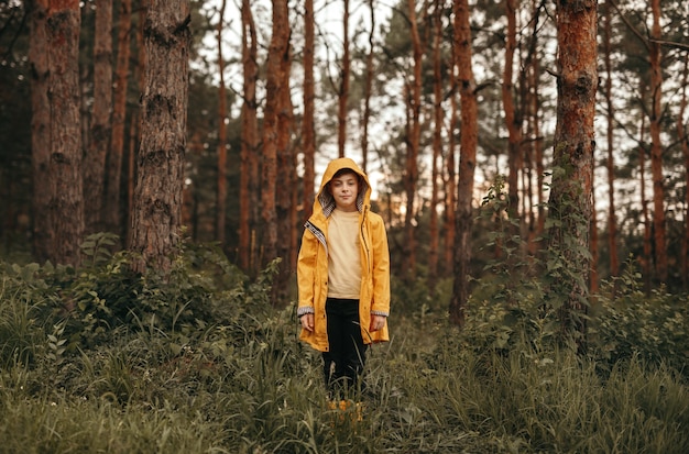 menino com capa de chuva na floresta de verão