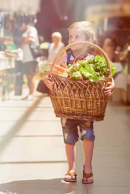 Menino com cesta de frutas e legumes