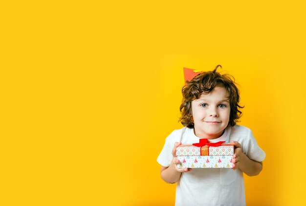 Menino com chapéu de festa segurando um presente