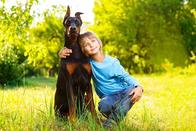 Foto menino com dobermann no parque de verão.