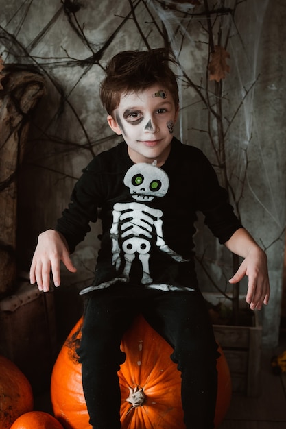 Foto menino com fantasia de esqueleto no carnaval de halloween em um cenário incrível sentado