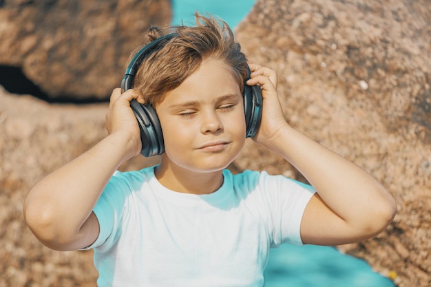 Menino com fones de ouvido ouvindo música ao ar livre