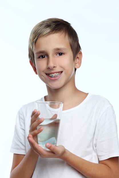 menino com fundo branco usando aparelho nos dentes Pulverize um antisséptico bucal desinfetante na garganta