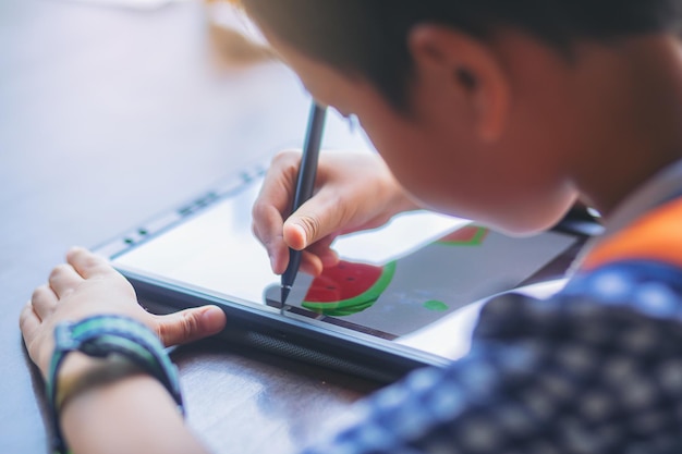 Menino com lápis digital desenhando e pintando em um tablet em casa