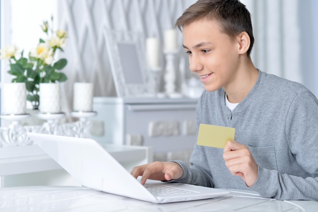 Menino com laptop e cartão de crédito