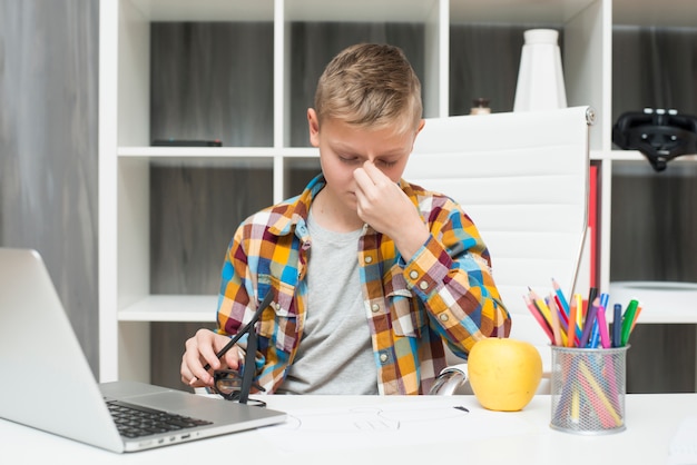 Menino, com, laptop, escrivaninha, e, cansado, expressão