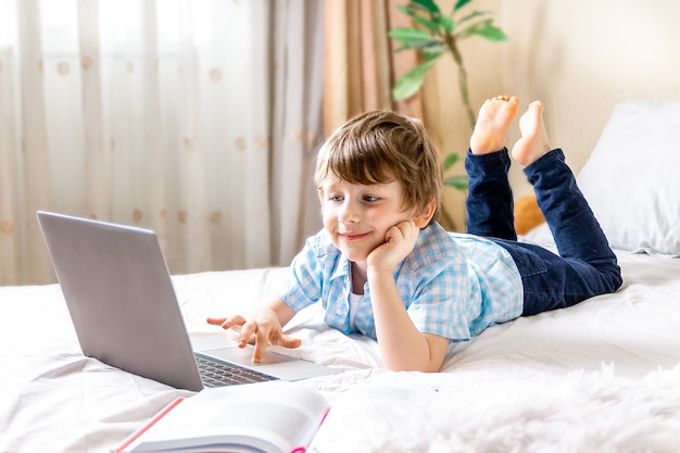 Menino com laptop na cama