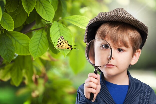 Menino com lupa olhando borboleta