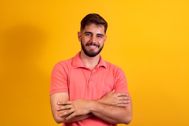 Menino com os braços cruzados sorrindo sobre fundo amarelo com espaço livre.