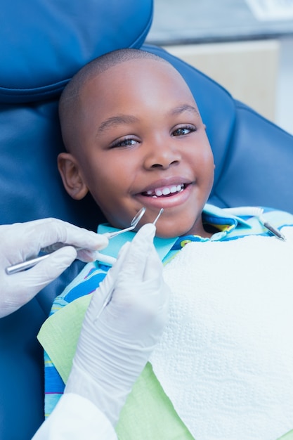 Menino com os dentes examinados por dentista