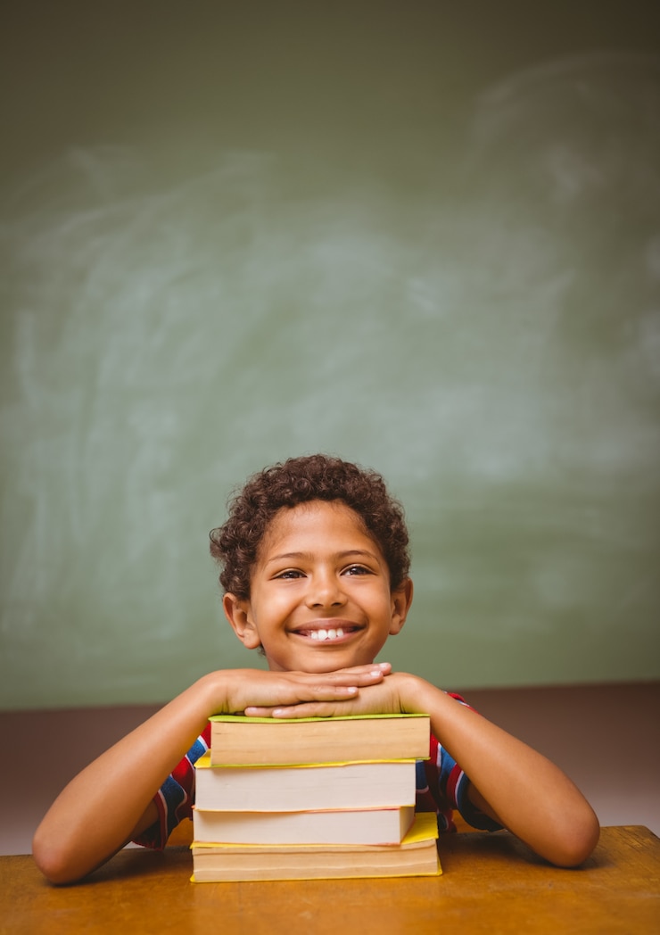 Foto menino com pilha de livros na sala de aula