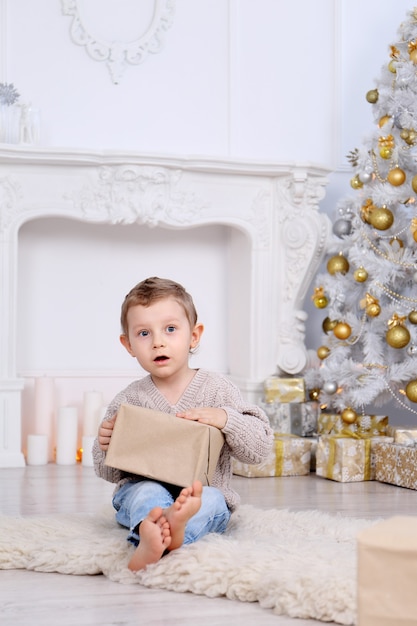 Menino com presentes debaixo da árvore de natal