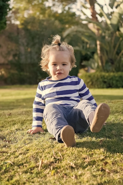 menino com rosto feliz na grama verde descalço