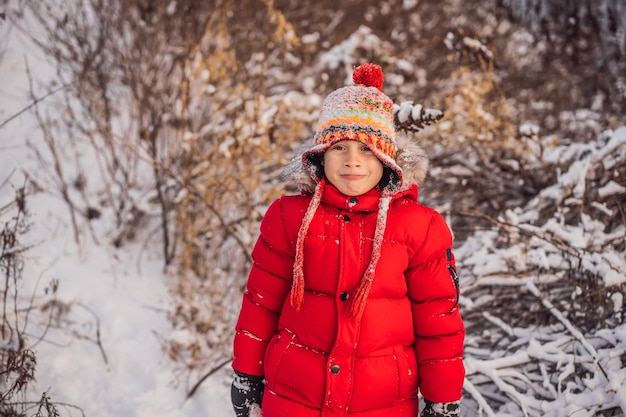 Menino com roupas da moda vermelha brincando de lazer ativo ao ar livre com crianças no inverno em dias frios menino