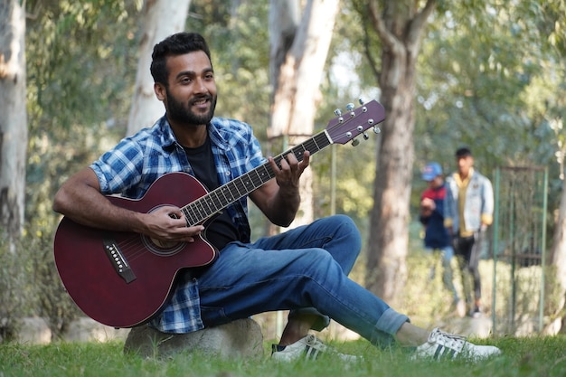 Menino com seu violão e tocando violão no parque