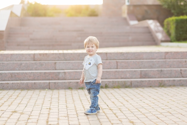 Menino com sorriso feliz andando no parque ao ar livre