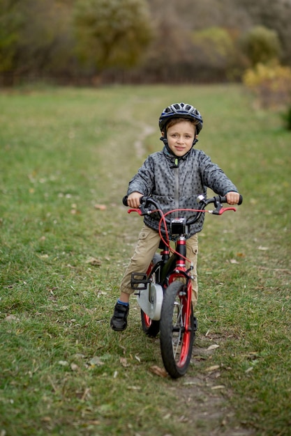 Menino com um capacete em uma bicicleta anda no parque.