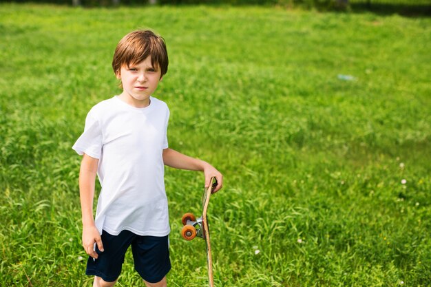 Menino com um skate, em um fundo de grama