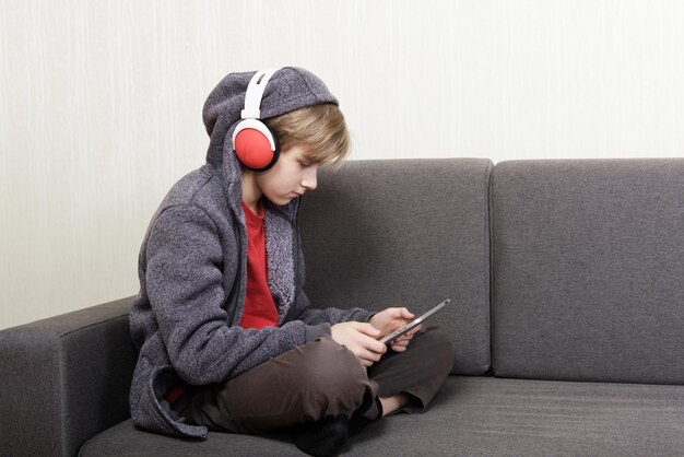 Menino com um tablet digital sentado no sofá