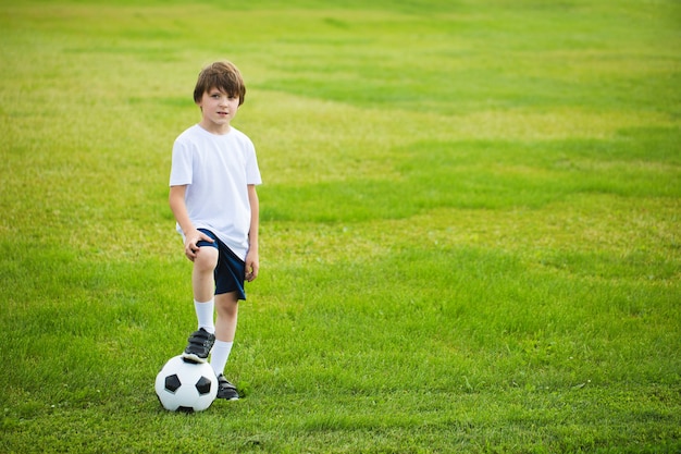 Menino com uma bola de futebol em um campo de futebol