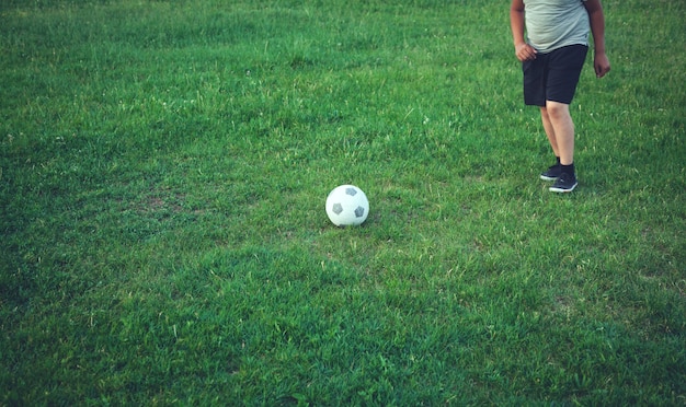 Menino com uma bola de futebol em um campo de futebol.