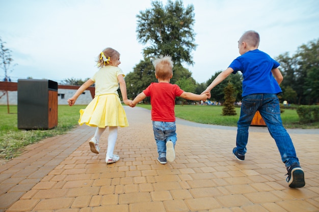 Menino com uma menina andando no parque no verão em dia de sol. amiguinhos de mãos dadas ao ar livre. infância feliz. as crianças emocionais caminhando ao ar livre. irmão e irmã brincando na natureza