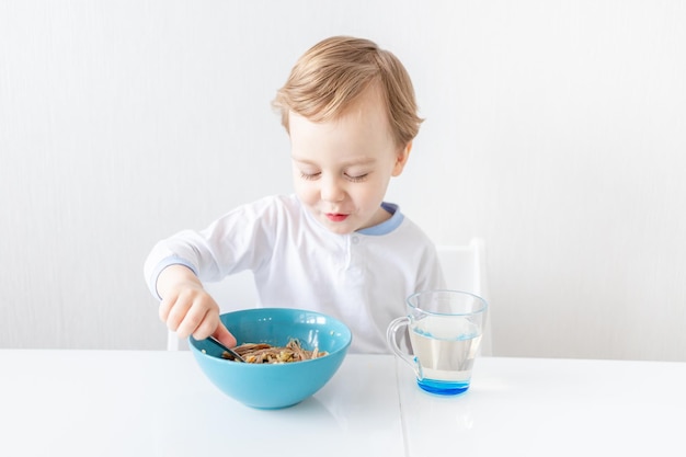 Menino come com colher em casa o conceito de alimentação e nutrição infantil