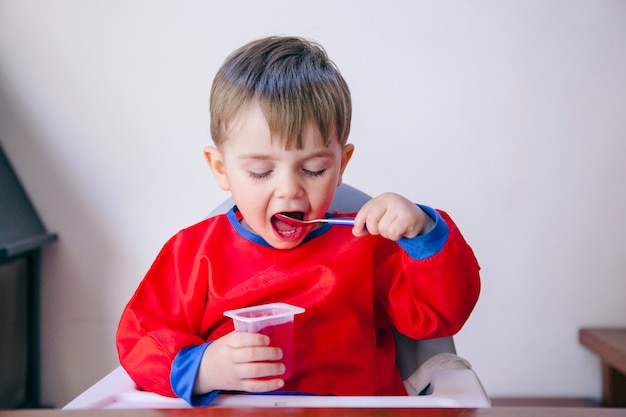 Menino começando a comer sozinho, sem a ajuda dos pais. Família e conceito de dieta saudável.