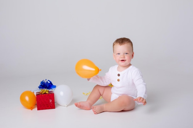 Menino comemora aniversário com balões e presentes em um fundo branco no estúdio