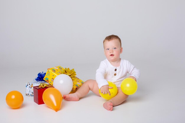 Menino comemora aniversário com balões e presentes em um fundo branco no estúdio