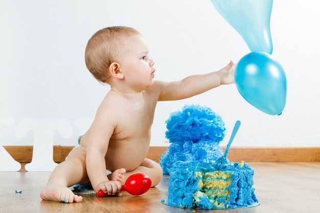 Menino comemorando seu primeiro aniversário com bolo gourmet e ba