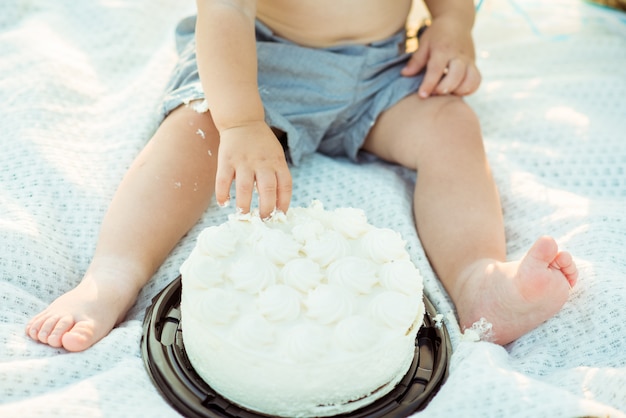 Menino comendo com as mãos bolo branco