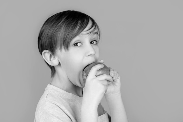 Menino comendo maçã e sorrindo Menino sorri e tem dentes brancos e saudáveis Garotinho comendo maçã Maçãs de menino mostrando Criança com maçãs Preto e branco