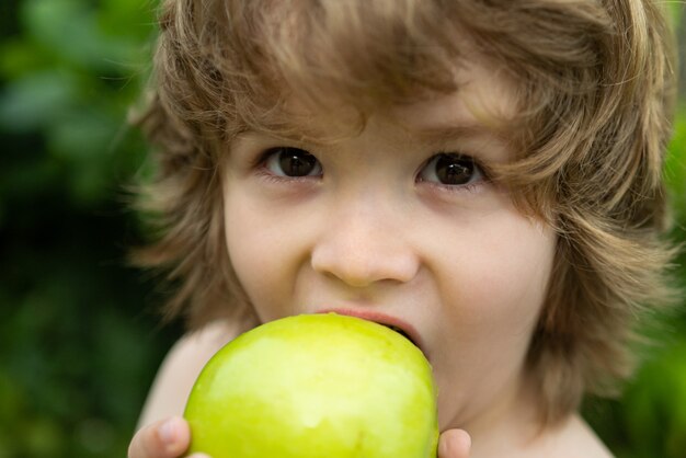 Menino comendo uma maçã em um parque na natureza